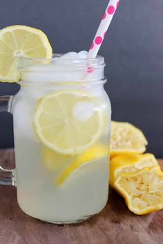 a mason jar filled with lemonade on top of a wooden table next to sliced lemons