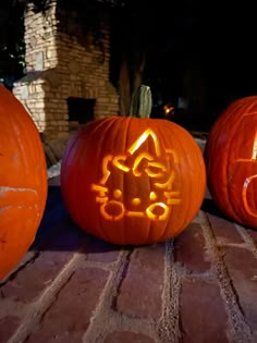 three carved pumpkins sitting on top of a brick floor