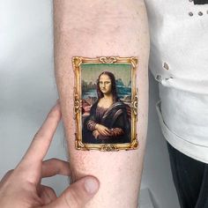 a person with a tattoo on their arm is holding up a painting that looks like the monaine