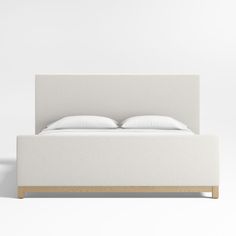 a bed with white linens and pillows on it's headboard is shown