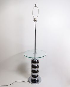 a glass table with two balls on it and a lamp in the middle that is turned on