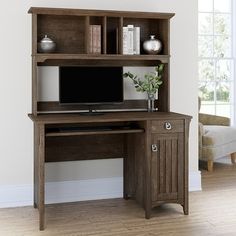 a computer desk sitting on top of a hard wood floor next to a white wall