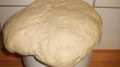 a ball of dough sitting on top of a white vase in front of a wall