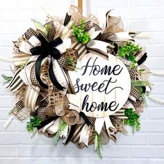 a wreath that says home sweet home hanging on a wall next to a brick wall