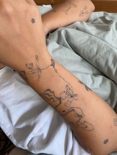 a person laying in bed with tattoos on their arm