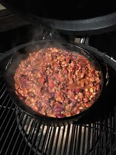 a large skillet filled with food cooking on top of an open grill