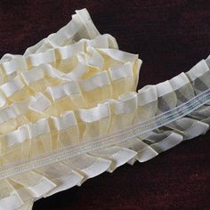 a piece of fabric with white ruffles is laying on a brown tablecloth