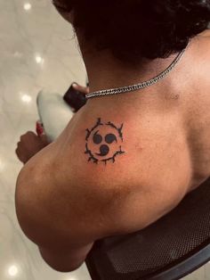 the back of a woman's shoulder with a skull tattoo on her left side