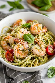 pasta with shrimp and pesto in a white bowl on top of a striped towel