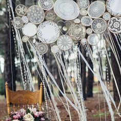 a wooden chair sitting in the middle of a forest filled with lots of hanging decorations