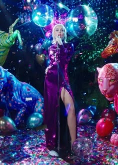 lady in purple dress standing on stage surrounded by balloons