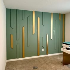 an empty room with green walls and gold lines painted on the wall, along with a computer desk