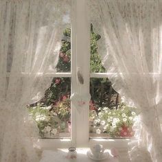 a window with white curtains and pink flowers