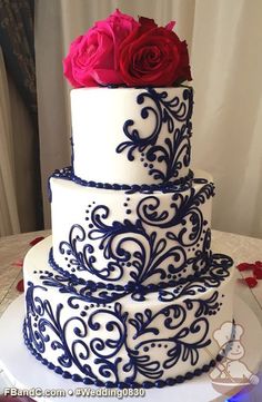 a three tiered wedding cake with blue and white designs on the side, decorated with red roses