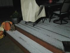 an outdoor area with white rugs, chairs and table in the background at night