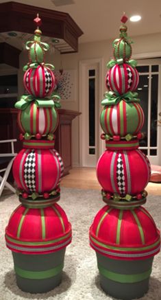 three red and green christmas ornaments sitting on top of a white carpeted floor in a living room