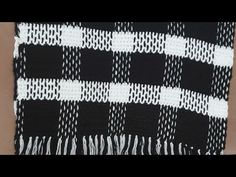 a black and white scarf with fringes hanging from it's end, in the shape of a checkerboard pattern