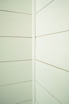 the corner of a white painted wall with vertical lines on it's sides and one line at the end