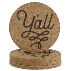 two cork coasters with the word y'all on them in black ink, sitting next to each other