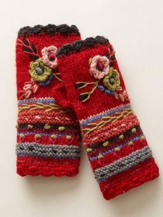 two red knitted mittens with flowers and stripes on the bottom, one is made out of yarn