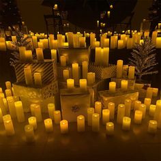 many lit candles are on the ground in front of christmas trees