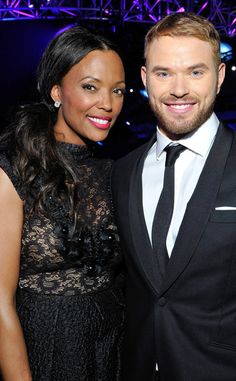 a man in a suit and tie standing next to a woman wearing a black dress