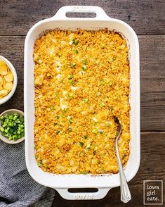 a casserole dish with potatoes and peas in it on a wooden table next to two bowls