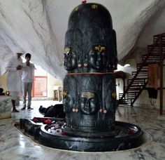 two men standing next to a large statue in a room with marble floors and walls