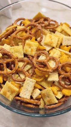 a glass bowl filled with cheesy crackers and pretzels