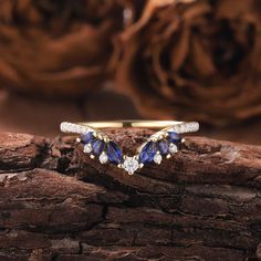 a gold ring with blue and white stones on it sitting on top of a piece of wood