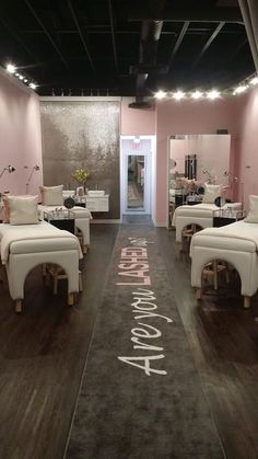 the inside of a salon with white chairs and pink walls, decorated in japanese writing