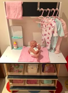 a baby sitting on top of a pink blanket next to a shelf filled with clothes