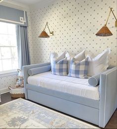 a couch with pillows on it in front of a wallpapered room and window