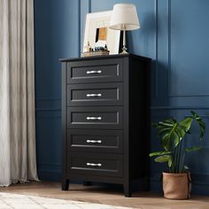 a black chest of drawers in a room with blue walls and a potted plant