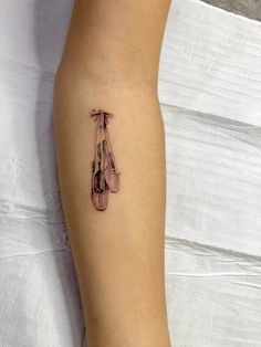 a woman's arm with a tattoo on it that has ballet shoes hanging from it