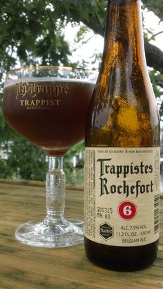 a bottle of beer next to a glass filled with liquid on top of a wooden table