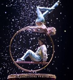 two people are performing on top of each other in a ring with snow falling around them