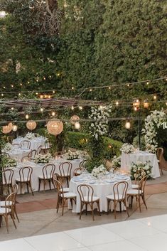 an outdoor dining area with tables and chairs set up for a formal dinner in the garden