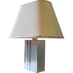 a lamp that is on top of a white surface with a beige shade over it