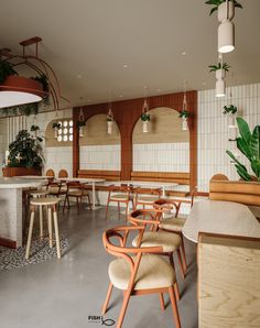 an empty restaurant with wooden chairs and plants on the wall behind them, along with tiled walls