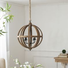 a wooden chandelier hanging from a ceiling in a room with white flowers on the table