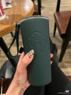 a woman holding up a starbucks cup with her hand on the coffee cup and playing dice