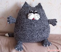 a gray cat stuffed animal sitting on top of a bed