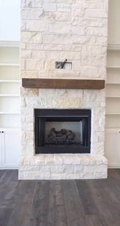 an empty fireplace in a living room with white walls and wood flooring on either side