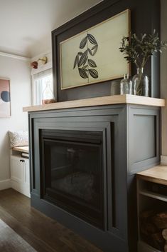 a living room with a fire place and some vases on top of the fireplace