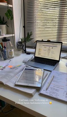 an open laptop computer sitting on top of a white desk next to papers and pens