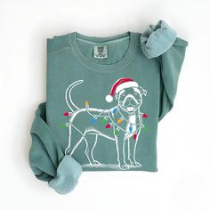 a green shirt with a dog wearing a santa hat and lights on it's chest