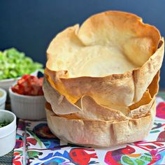 a large pot pie sitting on top of a colorful table cloth next to bowls of vegetables