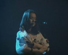 a woman holding a baby in her arms while standing next to a microphone on stage