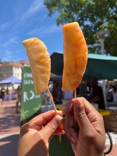 a person holding two pieces of fruit on a stick